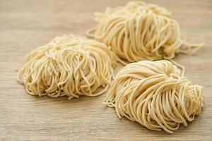 raw ramen noodle in wood plate on wooden table background. fresh egg ramen noodles and wooden background photo