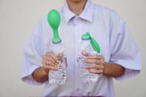 Student study  science experiment, hold two bottles with green balloons on the top of bottles. Concept, science experiment about reaction of chemical substance, vinegar and baking soda. photo