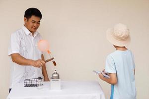 Asian man teacher is demostrating science exeriment about reaction of balloon on test tube is burned from lantern for his student. Science activity. photo