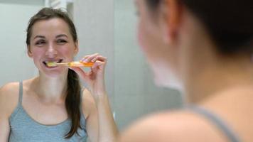 mooi vrouw poetsen haar tanden in een badkamer in de ochtend. ochtend- hygiëne. video