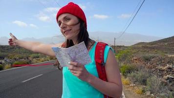 voyageur femme auto-stop sur une ensoleillé route et marche. randonneur femme à la recherche pour une balade à début une périple sur une ensoleillé pays route. lent mouvement video