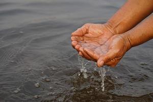 Closeup hands hold some water in river. Concept, explore, inspect clarify and quality of water from natural source. Ecology survey. Environment conservation. photo