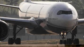 Phuket, Thaïlande février 24, 2023 - Airbus a330 de classe solaire compagnies aériennes roulage à phuket aéroport. avion de ligne dans rétro-éclairage. avion sur le taxiway, paume des arbres dans le Contexte video