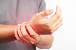 Asian male arms holding his painful wrist caused by exercise. Asian man hand holding his pain wrist isolated on background photo