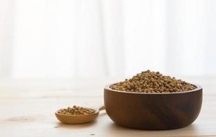 Coriander seeds in wooden bowl and spoon on wooden table background photo