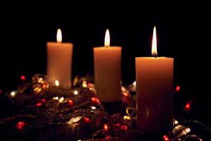 Flame candles with decorative lights on black table background photo