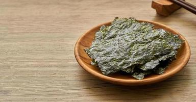 roasted nori laver seaweed snack in wood plate on wooden table background. nori laver seaweed crispy in wood plate on wooden table background. photo