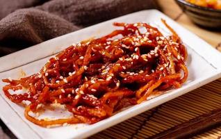 Seasoned dried shredded squid ojingeochae muchim with kimchi on wood table photo