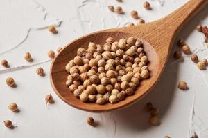 Coriander seed in spoon on white background photo