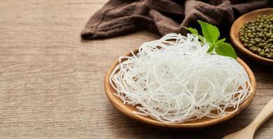 Asian vermicelli or cellophane noodles and mung green bean in wooden plate on wood table background. glass noodle photo