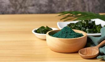 laminaria o quelpo algas marinas y espirulina polvo en madera cuenco y cuchara antecedentes. espirulina polvo con Konbu y alga comida en madera mesa antecedentes foto