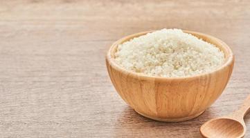 heap of short grain rice in wood bowl on wooden table background photo