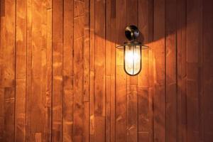 switched on lamp bracket at the wooden wall photo