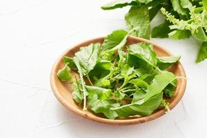 verde santo albahaca hojas de hoja en madera cuenco en mesa blanco antecedentes. Fresco verde santo albahaca hojas de hoja. santo albahaca foto