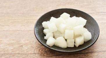 crunchy Korean pickled radish in plate on wood table background. white pickled radish. pickled radish on wood background photo