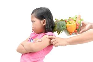 girl with expression of disgust against vegetables photo