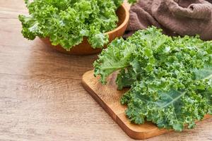fresh green Kale leaves bunch leaf cabbage in wood plate and bowl on wooden table background. green kale or leaf cabbage photo