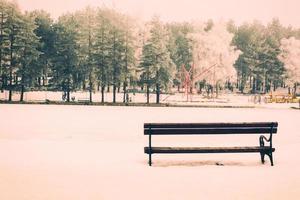 banco en el invierno hora foto