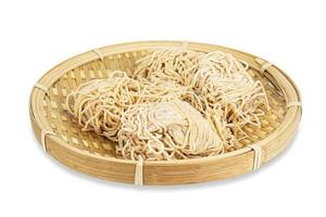 Chinese dry egg noodles in wooden plate isolated on white background photo