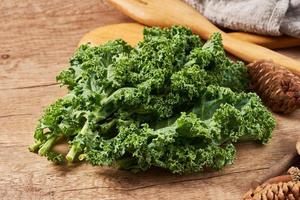 concept of fresh kale leaves salad on wooden table background. green kale leaves salad food in the kitchen. spoon, fork photo