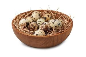close up quail eggs in wooden bowl and straw nest isolated on white background with clipping path photo