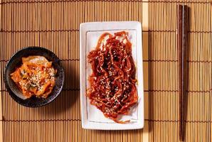 sazonado seco triturado calamar ojingeochae muchoim con kimchi en madera mesa foto