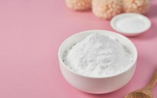 concept of collagen powder in a wood bowl and spoon on pink table background. protein intake. flower and plant. top view flat lay. collagen, collagen powder, fiber photo