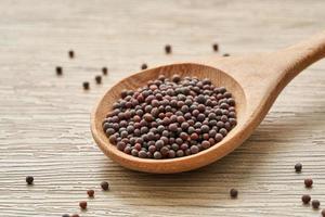 black mustard seed in wood spoon on wooden table background photo