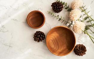 top view mock-up table setting, wooden bowls, and flowers on white marble background. flat lay photo