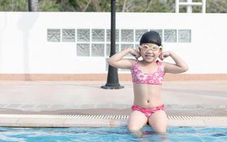 cute asian girl show muscle in swimming pool photo