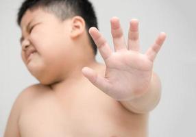 obese boy showing stop gesture on gray background photo