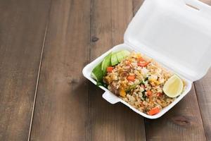 Hot food in foam box on wood table photo