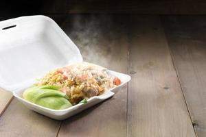 Hot food in foam box on wood table photo