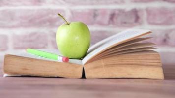 Preto para escola conceito com maçã em uma aberto livro em mesa video
