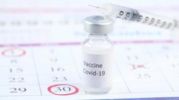 Gros plan du vaccin contre le coronavirus et de la seringue sur un calendrier avec cercle rouge video