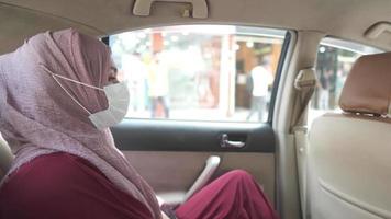 Side view of muslim woman with flu mask looking through a car window video