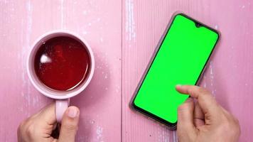 high angle view of man hand using smart phone with green screen and tea video