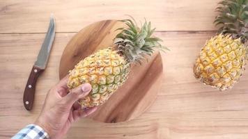 Putting fresh Pineapple on chopping board on table video