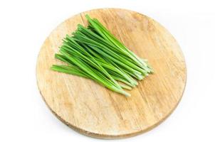 green onions on a wooden chopping board on white background photo