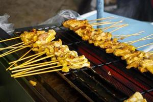 Thai street food BBQ,Pork satay grilling on stove or Thai style roasted pork at the market photo