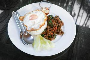 Thai stir-fried pork andfried egg and basil served with rice,Fried Basil with Pork Chop photo