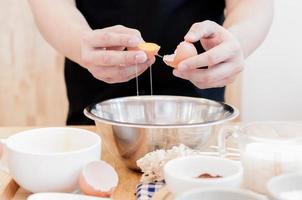 Man in the kitchen cooking a dough. Hands breaks an egg into a bowl ,hands pouring bitten egg ,Baking concept photo