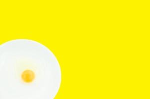 crudo huevo yemas en un blanco cuenco aislado en un amarillo fondo, a preparar para un alto proteína dieta tiene ayudó en el crecimiento de un de la persona cuerpo foto