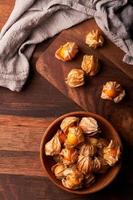 top view concept of cape gooseberry or physalis berry in a wooden bowl on a dining table in homemade style background with copy space photo