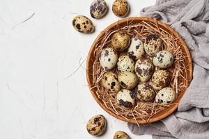 top view quail eggs in wooden bowl on white table background photo