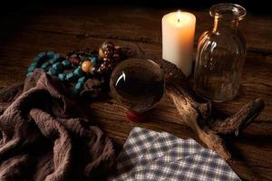 concept of fortune-telling on a wooden table and white candle with a crystal ball and tarot cards on dark background photo