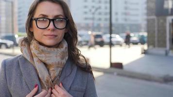 Porträt von ein Frau im Brille mit ein Frisur und neutral bilden auf ein Stadt Hintergrund Nahansicht video
