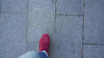 parte superior ver de de los hombres piernas en rojo zapatillas caminando en asfalto video