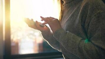 Female hands using smartphone against a blurred cityscape in the setting sun video