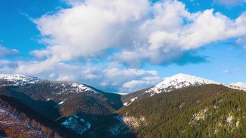 hiper lapso de nubes corriendo en azul cielo terminado increíble paisaje de Nevado montañas y conífero bosque en el pendientes video